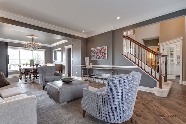 living area featuring crown molding, an inviting chandelier, wood finished floors, baseboards, and stairs