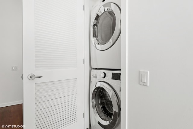 washroom featuring laundry area, wood finished floors, stacked washer and clothes dryer, and baseboards