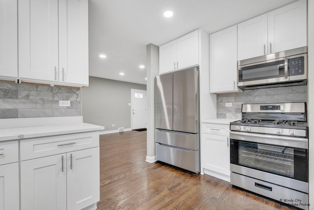 kitchen with white cabinetry, stainless steel appliances, tasteful backsplash, dark hardwood / wood-style flooring, and light stone counters