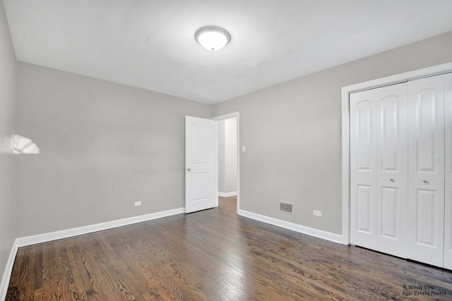 unfurnished bedroom with dark hardwood / wood-style floors and a closet