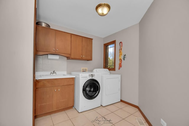 clothes washing area with independent washer and dryer, sink, cabinets, and light tile patterned floors