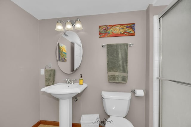 bathroom featuring a shower with shower door and toilet