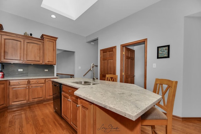 kitchen with sink, a breakfast bar area, dishwasher, a skylight, and a kitchen island