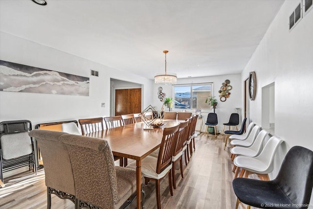 dining space featuring an inviting chandelier and light hardwood / wood-style floors