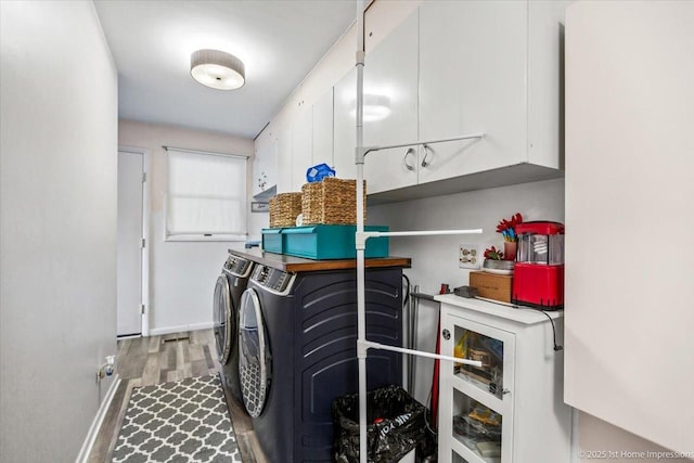 clothes washing area featuring hardwood / wood-style floors, washer and clothes dryer, and cabinets