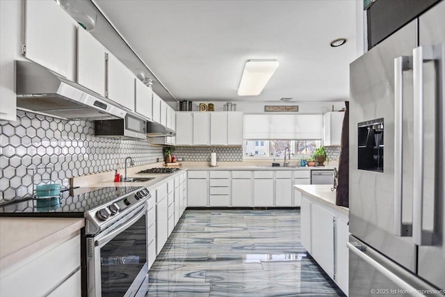 kitchen featuring stainless steel appliances, sink, white cabinets, and decorative backsplash