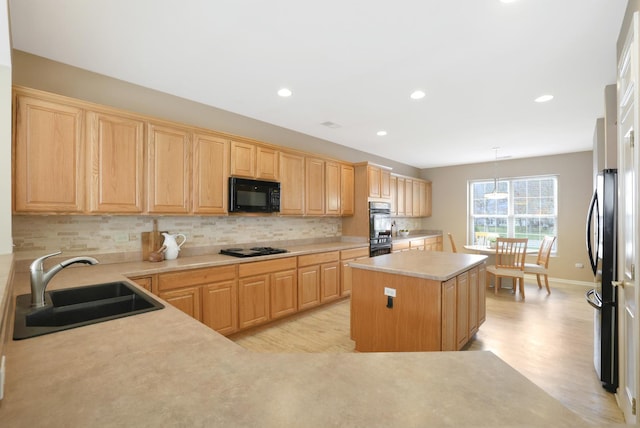 kitchen featuring pendant lighting, black appliances, a center island, light hardwood / wood-style floors, and sink