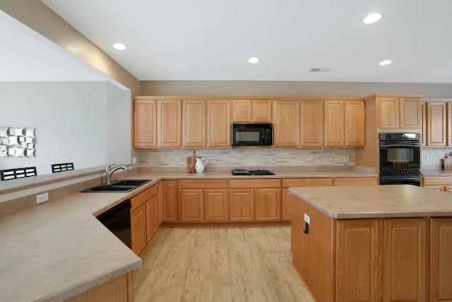 kitchen featuring backsplash, a kitchen island, black appliances, light hardwood / wood-style flooring, and sink