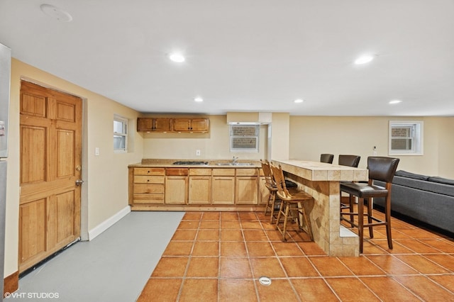 kitchen featuring light tile patterned floors, a kitchen bar, light countertops, and a sink