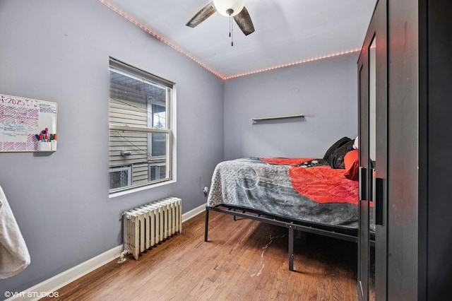 bedroom with baseboards, ceiling fan, light wood-style flooring, and radiator