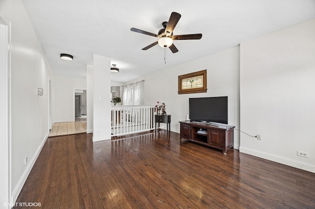 living room with dark wood-type flooring, a ceiling fan, and baseboards