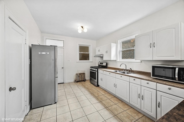 kitchen featuring appliances with stainless steel finishes, dark countertops, a sink, and white cabinets