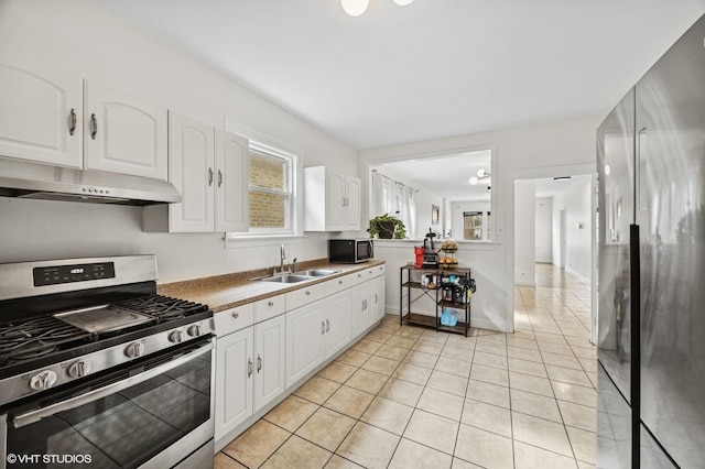 kitchen with under cabinet range hood, white cabinetry, appliances with stainless steel finishes, and a sink