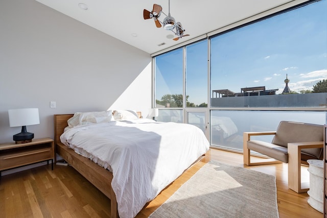 bedroom with floor to ceiling windows and light wood-type flooring