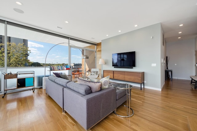 living room with a wall of windows and light wood-type flooring