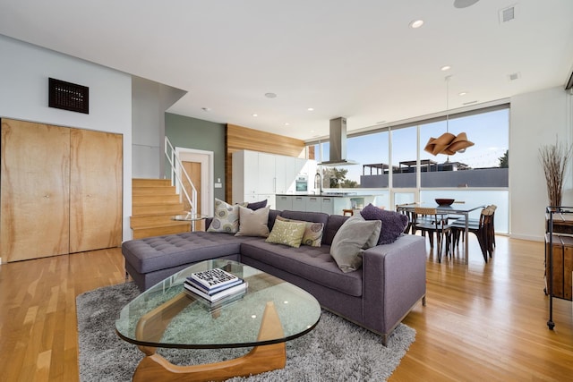 living room featuring sink, floor to ceiling windows, and light wood-type flooring