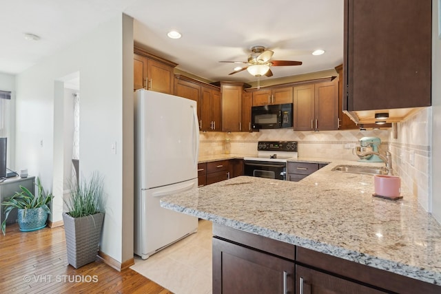 kitchen with range with electric stovetop, sink, white fridge, kitchen peninsula, and light stone countertops