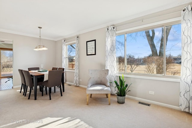 carpeted dining room with ornamental molding