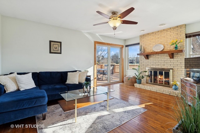 living room with a fireplace, wood-type flooring, and ceiling fan