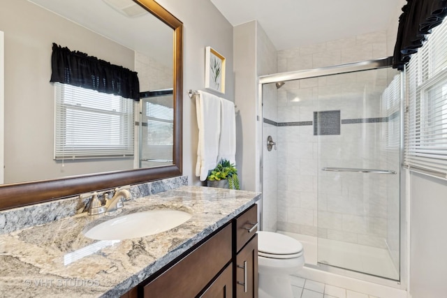 bathroom with vanity, a healthy amount of sunlight, toilet, and walk in shower