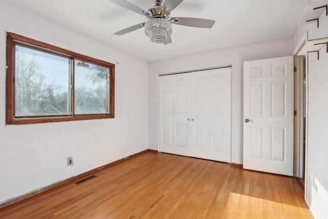 unfurnished bedroom featuring ceiling fan, light hardwood / wood-style floors, and a closet