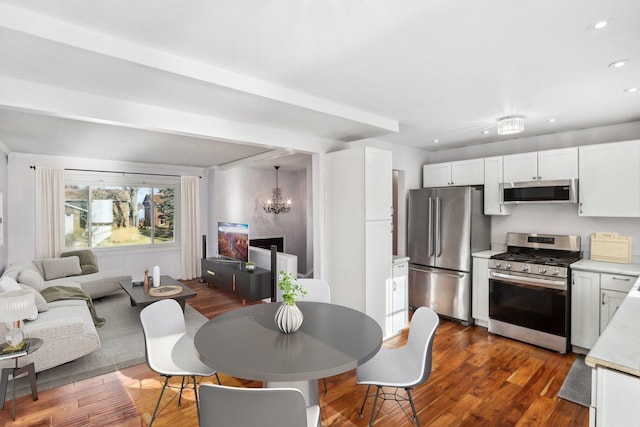 interior space featuring white cabinetry, appliances with stainless steel finishes, an inviting chandelier, and dark wood-type flooring