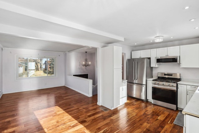 kitchen with dark wood-type flooring, white cabinets, and appliances with stainless steel finishes