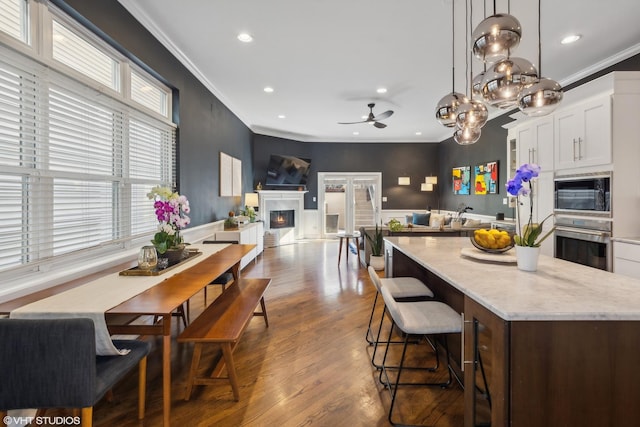 kitchen with white cabinets, a center island, decorative light fixtures, black microwave, and stainless steel oven