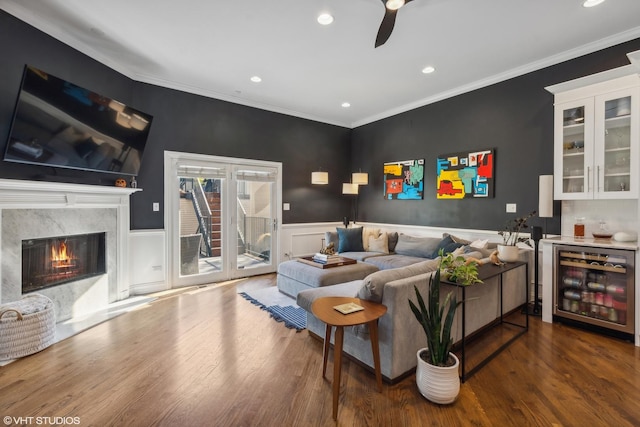 living room featuring dark hardwood / wood-style flooring, crown molding, beverage cooler, and a fireplace