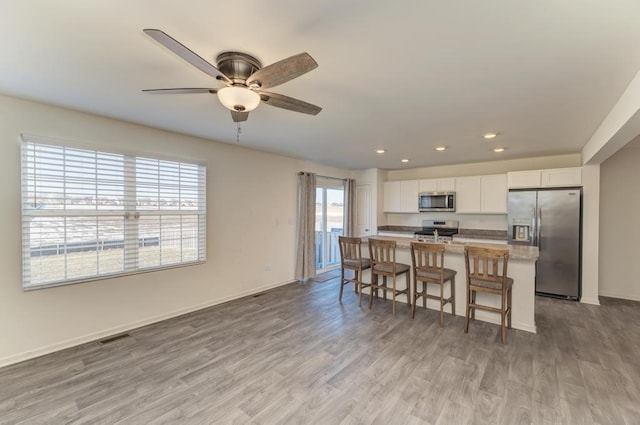 kitchen with a kitchen bar, white cabinets, a wealth of natural light, and appliances with stainless steel finishes