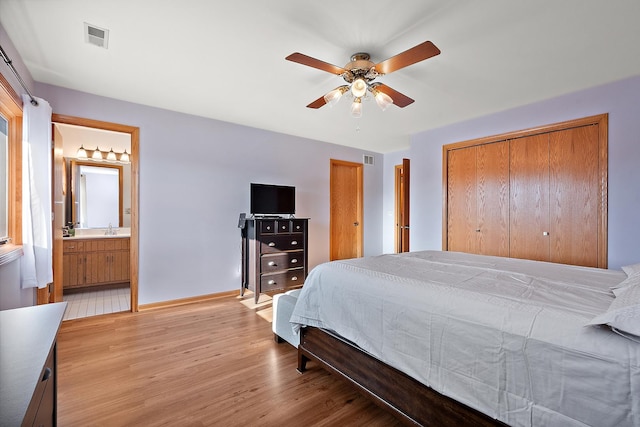 bedroom with ceiling fan, light wood-type flooring, sink, and ensuite bath