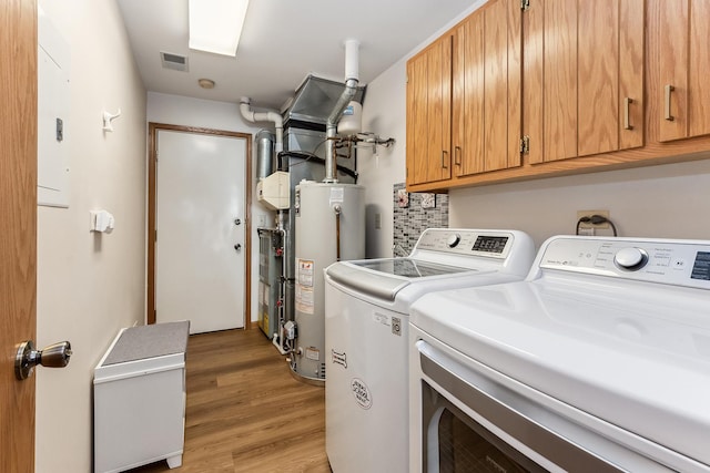 washroom featuring hardwood / wood-style flooring, cabinets, washer and clothes dryer, and gas water heater