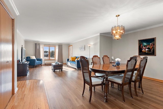 dining space featuring an inviting chandelier, ornamental molding, and light hardwood / wood-style flooring