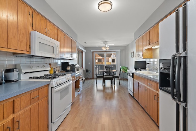 kitchen featuring sink, white appliances, light hardwood / wood-style flooring, ceiling fan, and decorative backsplash