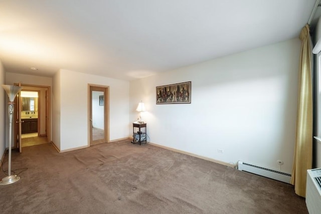 carpeted spare room with a baseboard heating unit