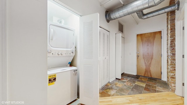 clothes washing area featuring stacked washer / dryer