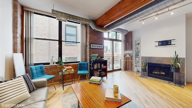 living room featuring brick wall, a tile fireplace, and wood-type flooring