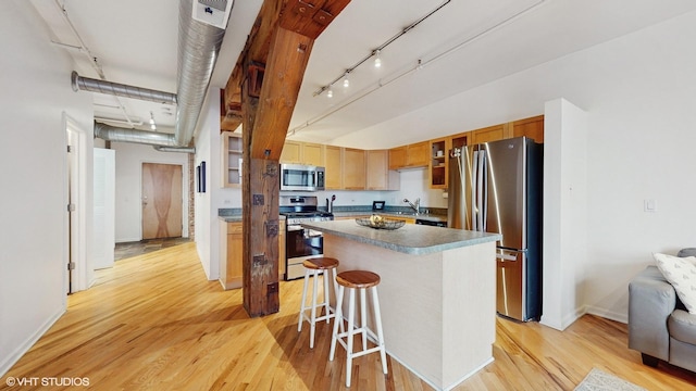 kitchen with stainless steel appliances, a kitchen island, light hardwood / wood-style flooring, and a breakfast bar