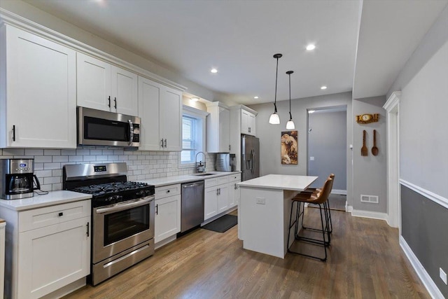 kitchen featuring a center island, white cabinetry, decorative backsplash, pendant lighting, and stainless steel appliances