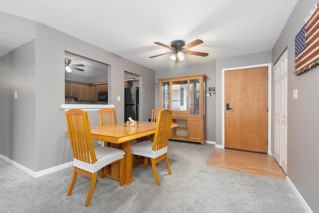 carpeted dining room with ceiling fan