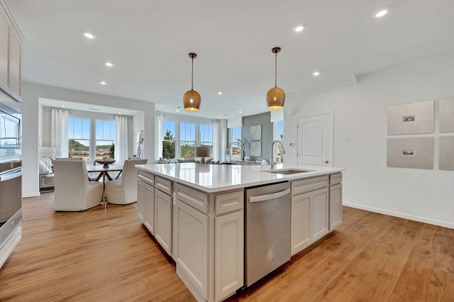 kitchen featuring light hardwood / wood-style floors, sink, decorative light fixtures, an island with sink, and stainless steel appliances