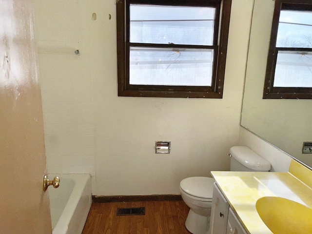 bathroom featuring hardwood / wood-style floors, toilet, vanity, and a bathing tub