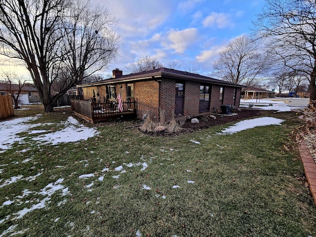 view of snow covered exterior with a deck and a lawn