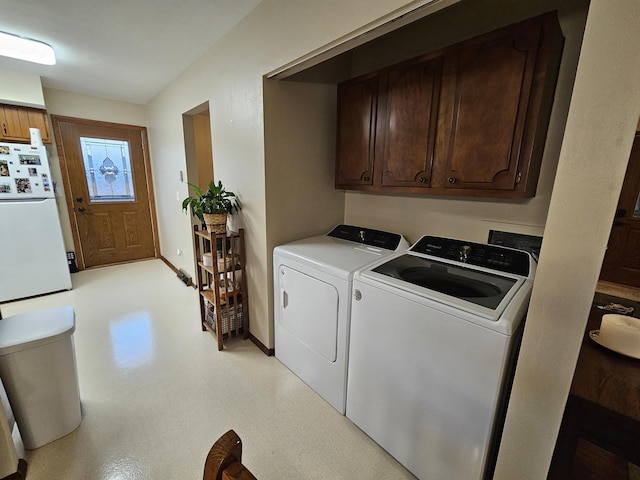 clothes washing area with cabinets and washing machine and clothes dryer