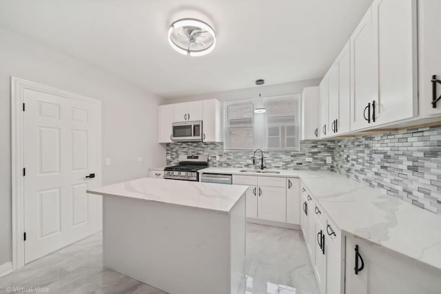 kitchen with a center island, white cabinetry, stainless steel appliances, sink, and light stone counters