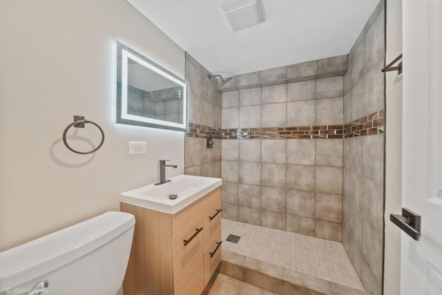 bathroom with tiled shower, toilet, and vanity