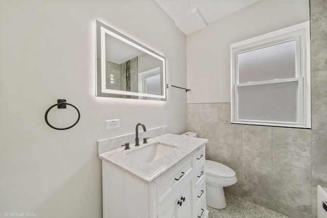 bathroom with toilet, tile walls, and vanity