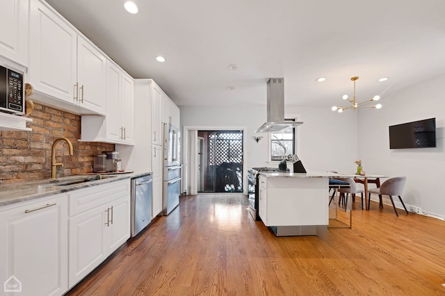 kitchen featuring white cabinets, appliances with stainless steel finishes, sink, island range hood, and light stone counters