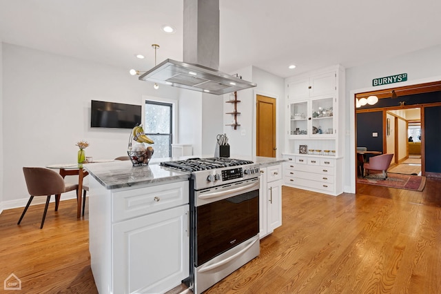 kitchen with light hardwood / wood-style flooring, white cabinetry, light stone countertops, island range hood, and gas stove