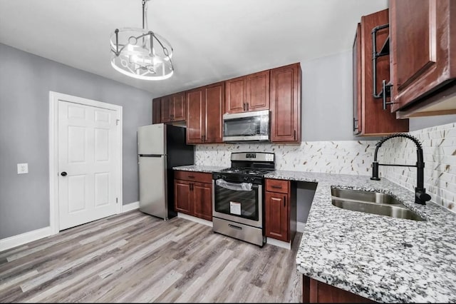 kitchen with sink, appliances with stainless steel finishes, hanging light fixtures, light stone counters, and a chandelier